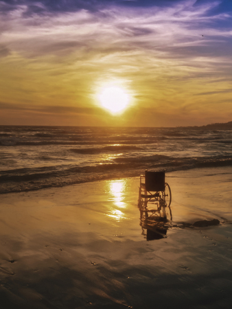 Sunset on the beach handicapped wheelchair. Backgroundの写真素材
