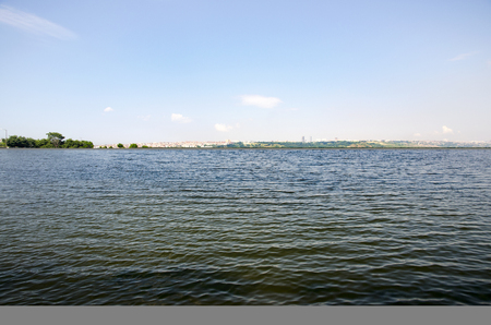 Lake, white clouds and green fields landscape. Lake Kucukcekmece (Turkish: Kucukcekmece Golu) is a lagoon located between the Kucukcekmece Esenyurt and Avcilar districts of the European portion of Istanbul Province, northwestern Turkey.の写真素材