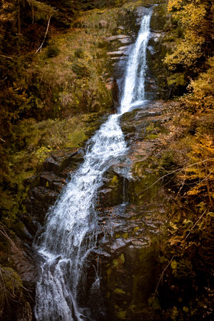 Waterfall KamieÅczyka in Szklarska PorÄba, Poland, cascades beautifully over rocky cliffs, set within a lush autumn forest and a peaceful mountain landscapeの写真素材