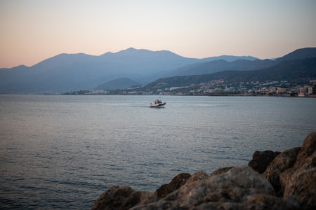 A picturesque view of a coastal bay with boats in Hersonissos, Crete. The serene waters meet the charming town, framed by the island's natural beauty.の写真素材