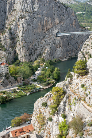 Omis bridge spans the Cetina River in Croatia, featuring scenic tunnels and a bridge with mountain views.の写真素材