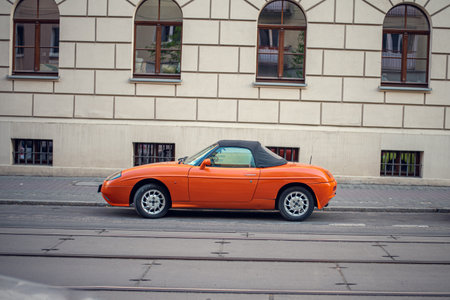 An orange Fiat Barchetta parked against the backdrop of PoznaÅ's charming historic architecture, Polandの写真素材