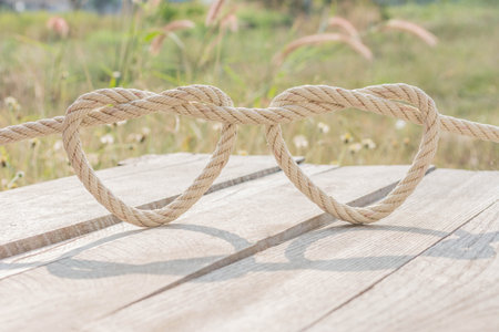 leash  rope into heart shape on wooden table with natural field backgroundの写真素材
