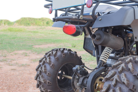 back side of Dirty ATV stands on the ground in rubber tree field
