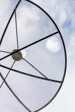 Satellite dish against cloudy sky with moon on sky . . Elements of this image furnished by NASAの写真素材