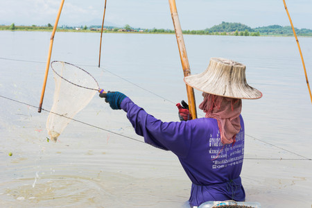 fisher man use square dip net fishing at lake with mountain and blue sky backgroundの写真素材