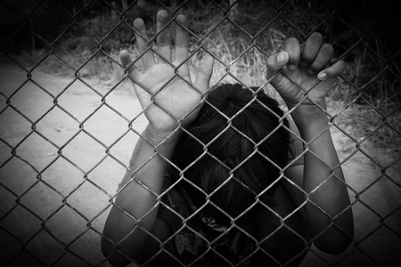 the boy holding the cage , imprisoned, retarded, Child Abuse in white toneの写真素材