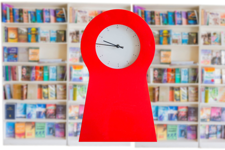 red clock on blurry book shelf backgroundの写真素材