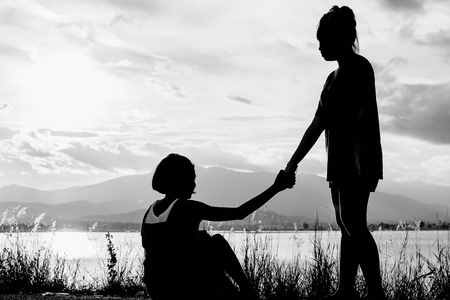 young girl help another girl to stand with lake view at sunset in white toneの写真素材