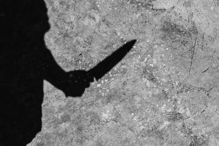 shadow of murdered holding knife on concrete background  in white tone with shadow edge