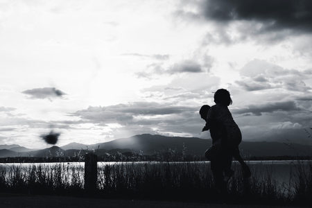 silhouette of girls pointing to sky at sunset in white toneの写真素材