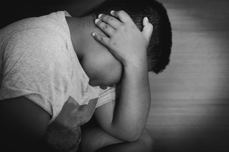 photo of children hand cover face with lower head, imprison, retarded, Child Abuse in white tone with shadow edgeの写真素材