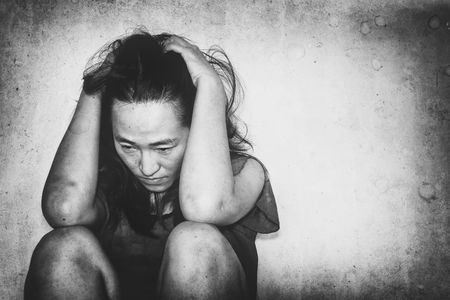 stressful and hopeless woman sitting on ground with shadow edge, dirt effect, in white toneの写真素材