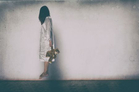 Mysterious Woman, Horror scene of scary ghost woman holding doll on white wall with black shadow の写真素材