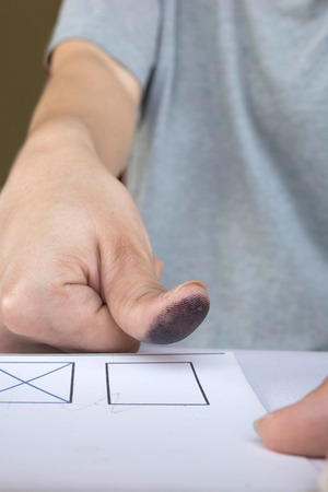 Stamping on card with a thumb print: Image contains thumb with ink stain with paper and ink stamp pad.(signing a contract concept)の写真素材