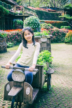 outdoor portrait of girl riding wooden motobike in park, vintage styleの写真素材