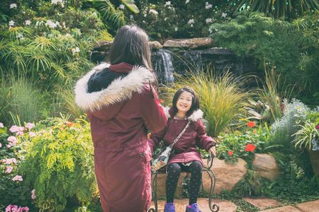 girl taking a photo of her sister outdoor in park with cellphone , vintage styleの写真素材