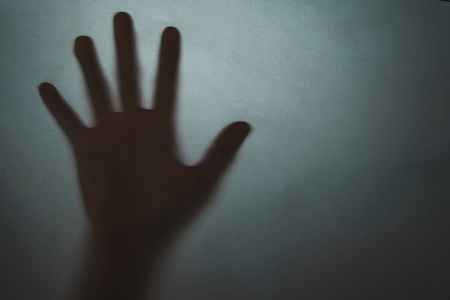 The concept of the shadow of hand behind paper, illuminated from behind.の写真素材