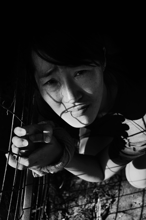 depress woman with hand tied in cage with light  in white tone(abuse concept)の写真素材
