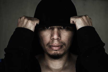 man in hood with scary face in the darkの写真素材