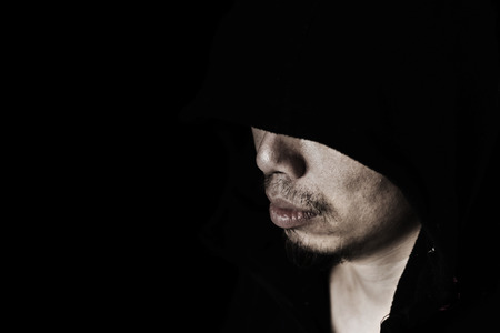 man in hood with lower head in the darkの写真素材