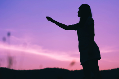 Silhouette of sadness woman standing against sunset backgroundの写真素材