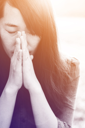 Woman praying in meadow at sunset with gradientの写真素材