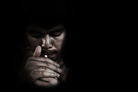 man lighting cigarette on black in white toneの写真素材