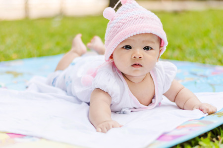 cute Asian baby lie prone on ground at parkの写真素材