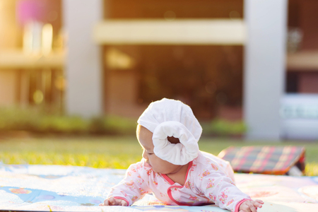 cute Asian baby lie prone on ground at parkの写真素材