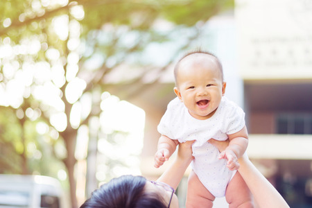 Asian  mother playing and taking care of  baby at parkの写真素材
