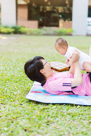 Asian  mother playing and taking care of  baby at parkの写真素材
