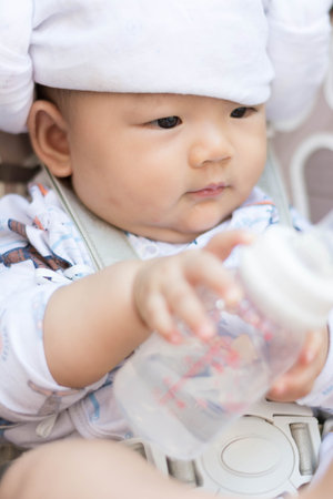 cute  Asian baby infant enjoy drinking water from bottle