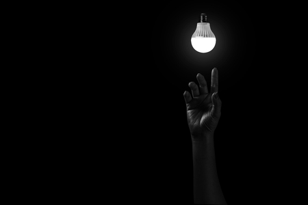 Hand reaching out to light in black, hopeful concept in white toneの写真素材