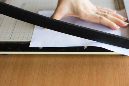 woman cutting paper with big paper cutter on tableの写真素材