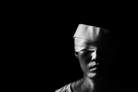 woman with bandages wrapped around her head standing in the darkの写真素材