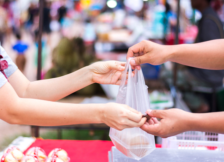 Customer paying bill by cash at open air market の写真素材