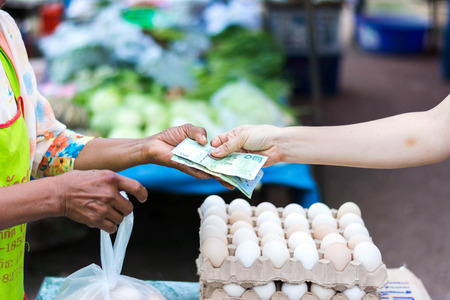 Customer paying bill by cash at open air marketの写真素材