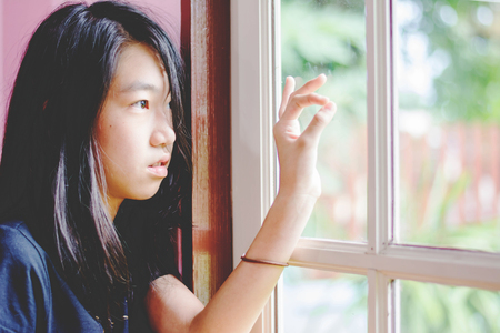 depress and hopeless girl with absent minded looking outsideの写真素材