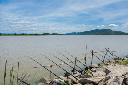 row of fishing rods fishing at lake sideの写真素材