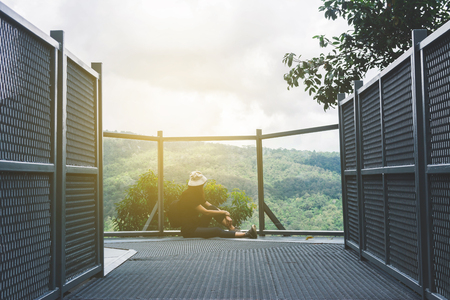 View of young woman sitting at the end of walk and enjoy view of  Chiangmai Mountain, Thailand.の写真素材