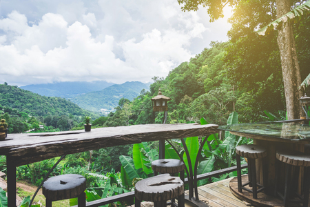 wooden table and chair against beautiful scene of mountainの写真素材
