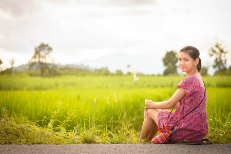Happy Asian girl enjoy in green rice field, countryside of Thailand at sunsetの写真素材