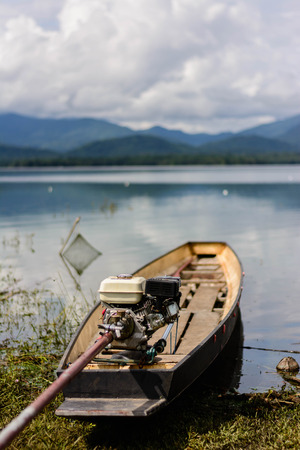 fishing boat with motor on lake with mountain backgroundの写真素材