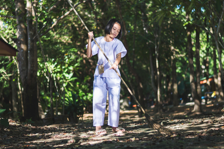 Asian girl cleaning the area of temple in forest , voluntary activitiesの写真素材