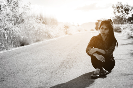 Blurry photo of Portrait  beautiful Asian woman in depression and frustration sitting on roadの写真素材