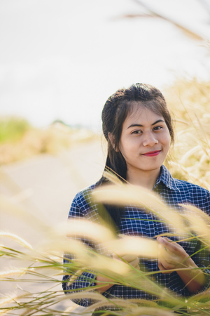 Woman enjoy grass flower in meadow at sunsetの写真素材