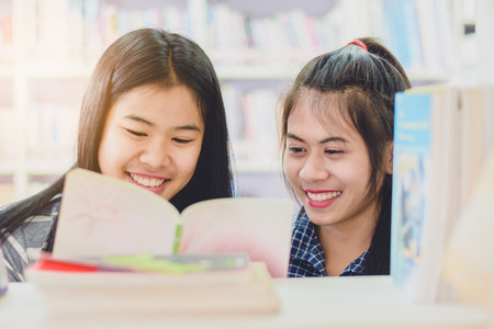 Portrait of clever Asian student reading and doing research in college libraryの写真素材