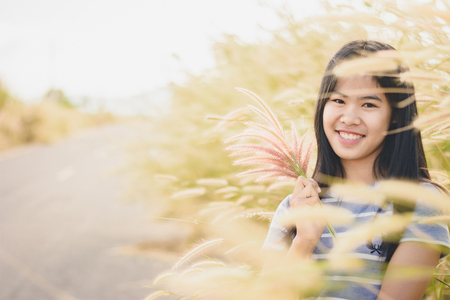 Woman enjoy grass flower in meadow at sunsetの写真素材