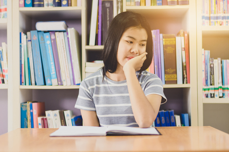 Portrait of clever Asian student reading and doing research in college libraryの写真素材